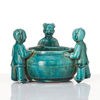 A turquoise glazed vessel supported by a group of boys, Qing dynasty, Kangxi (1662-1722).