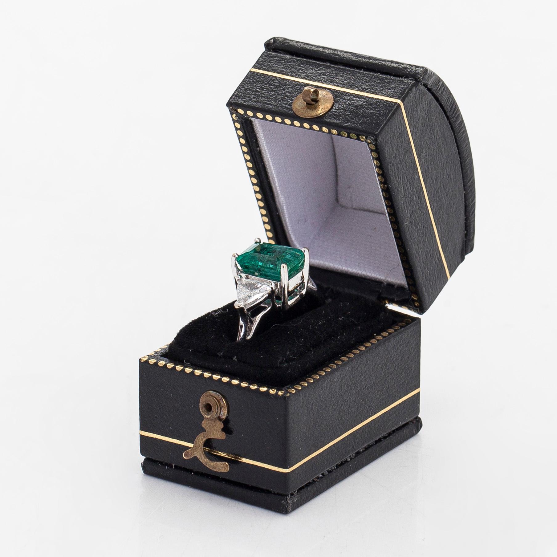 An 18K white gold ring, set with a Zambian emerald and trillion-cut diamonds.