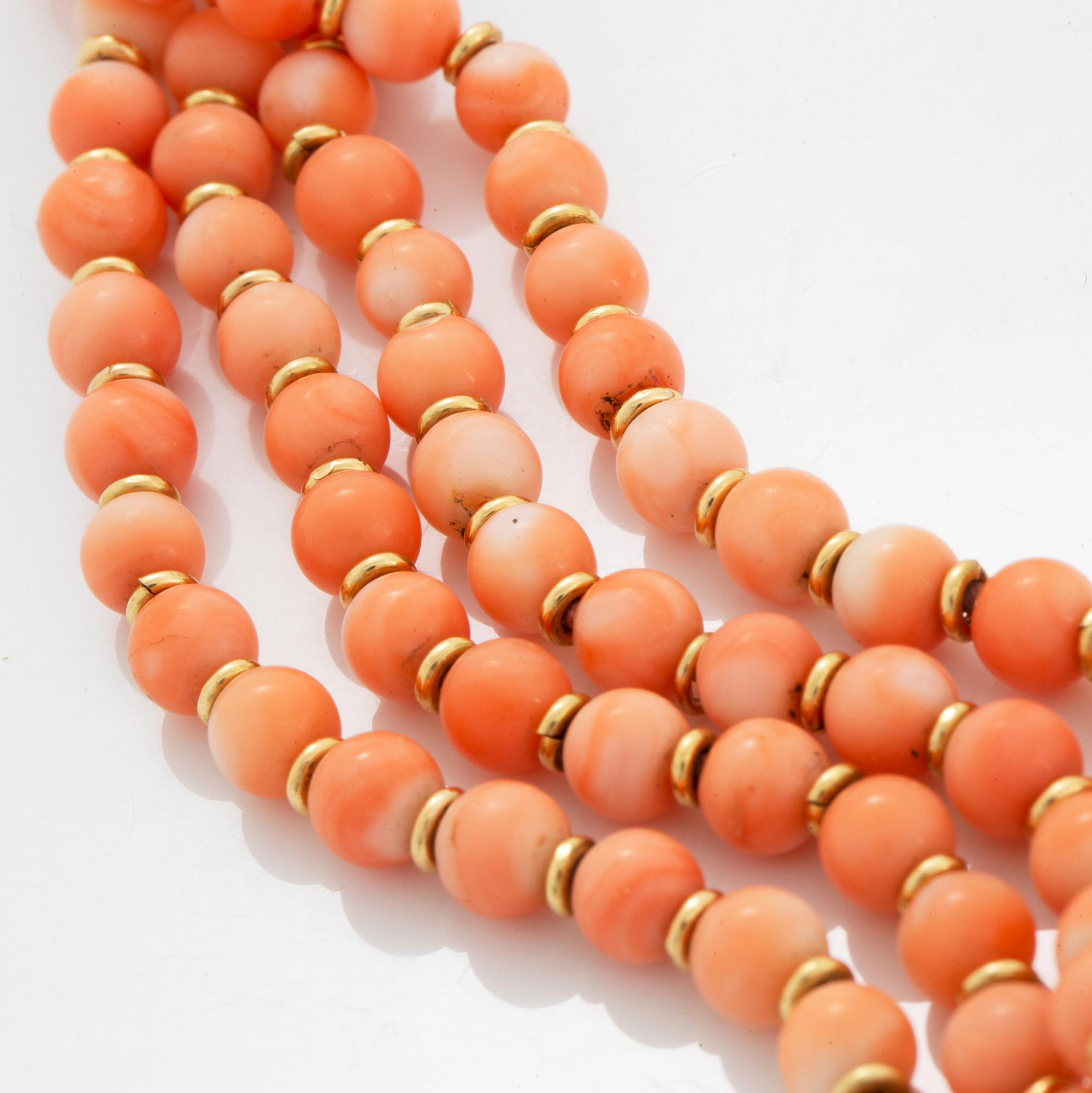 A four strand coral necklace with an 18K gold clasp set with coral and round brilliant-cut diamonds.