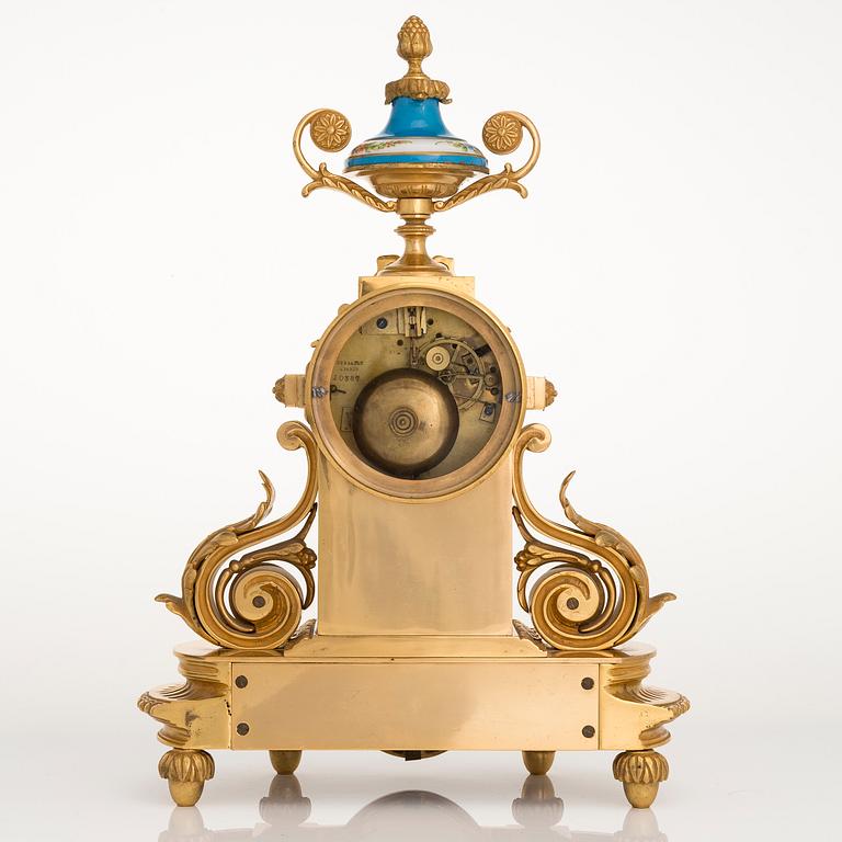 A mid-19th-century French gilt-brass mantel clock with a pair of candelabra by Dussault.