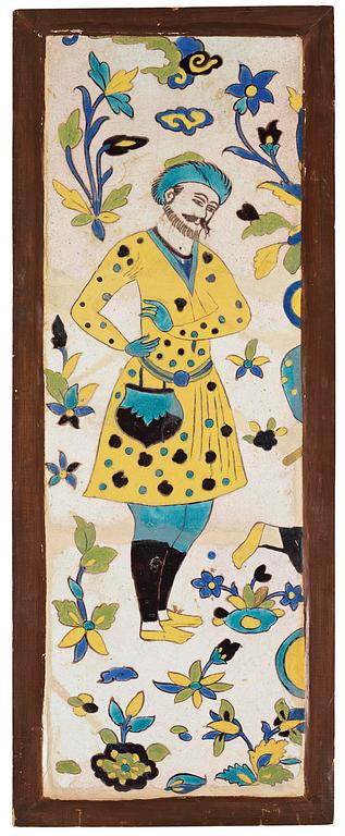 A glazed earthenware tile, Qajar dynasty Persia (Iran), 19th century. Man in yellow coat. Framed. Total dimensions 76 x 30 cm.