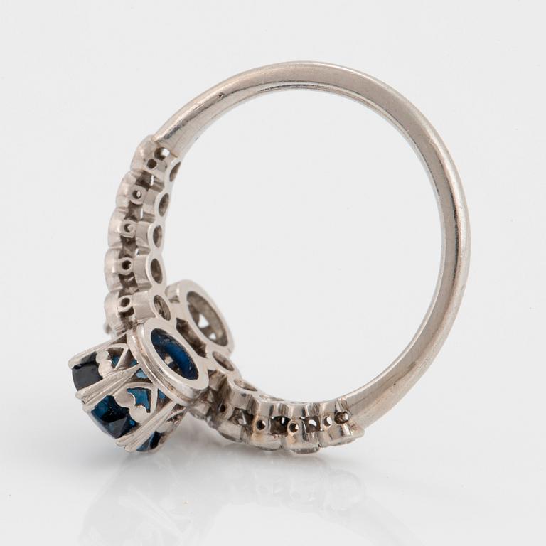 A platinum ring set with old-cut diamonds and a faceted sapphire.