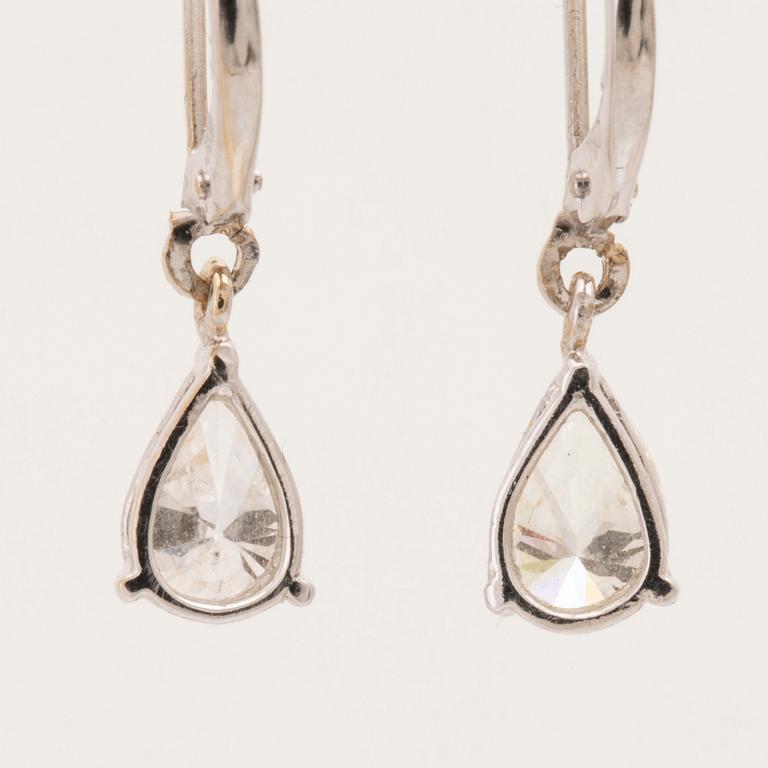 A pair of 18K white gold earrings set with pear cut diamonds.