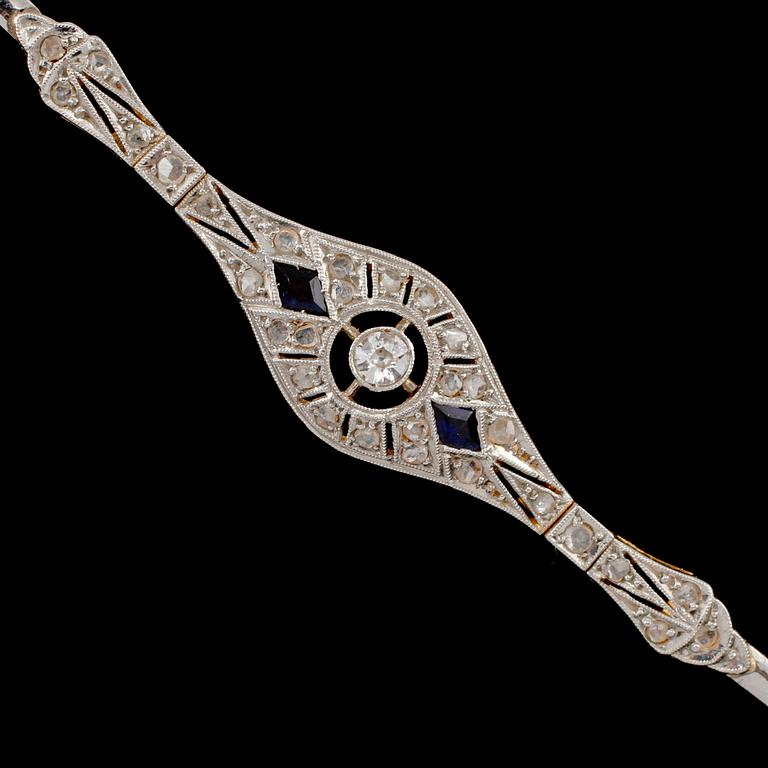 ARMBAND, 18k guld, fasettslipad diamant ca 0.08 ct, 2 blå safirer samt rosenstenar, 1900-talets första hälft. Vikt 8 g.
