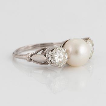 An 18K white gold ring set with a cultured pearl and two round brilliant-cut diamonds.