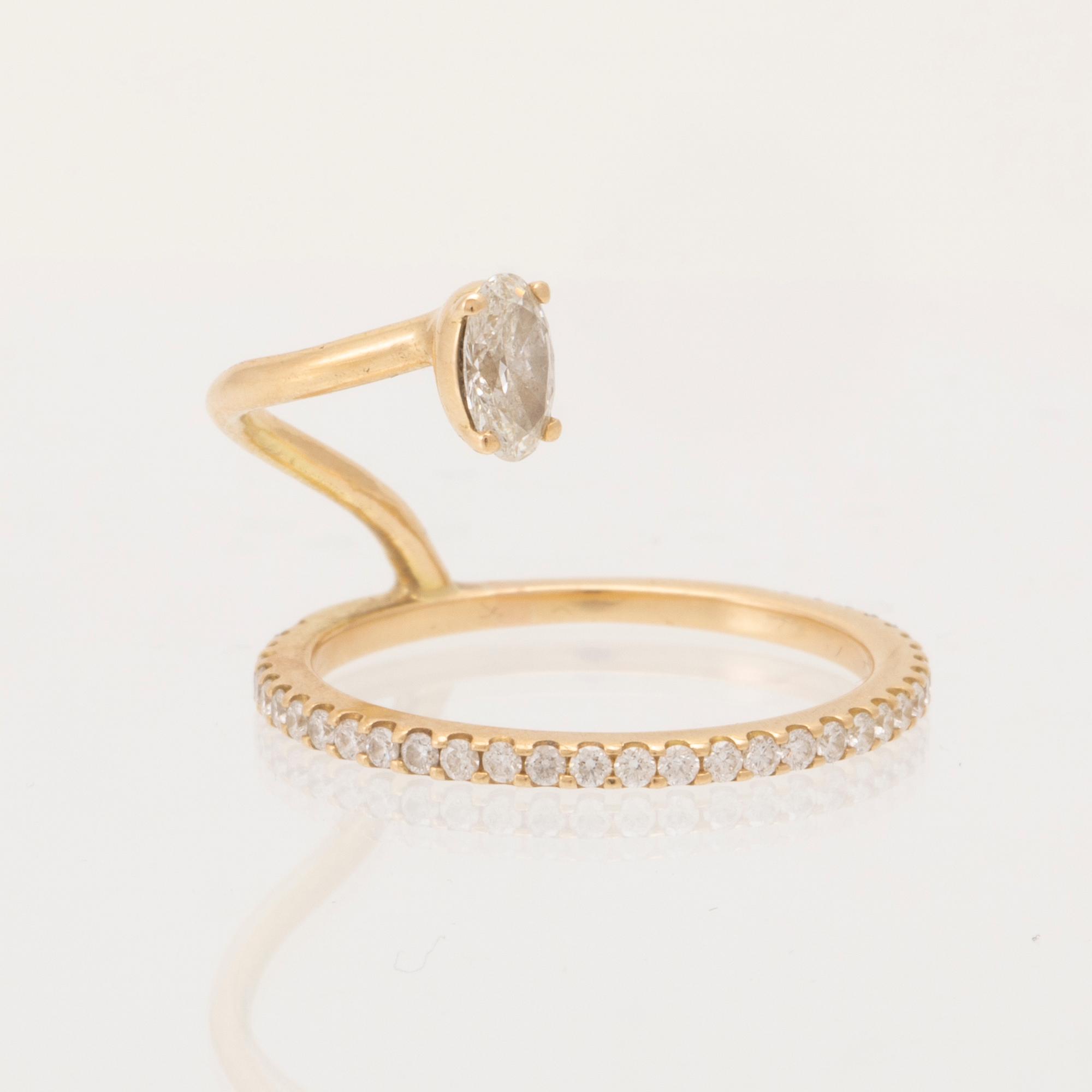 An 18K gold ring set with an oval cut and round brilliant cut diamonds by LWL Jewelry.