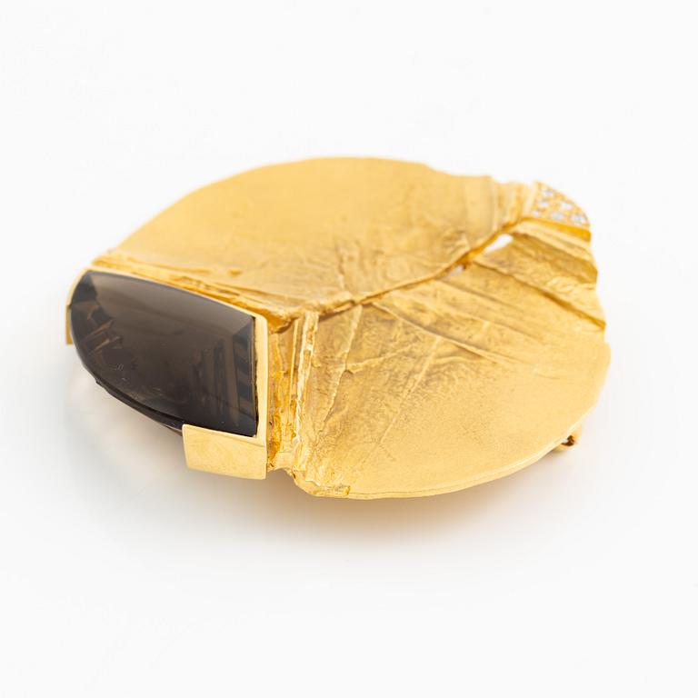 Brosch, 18K guld med fantasislipad rökkvarts och runda briljantslipade diamanter.
