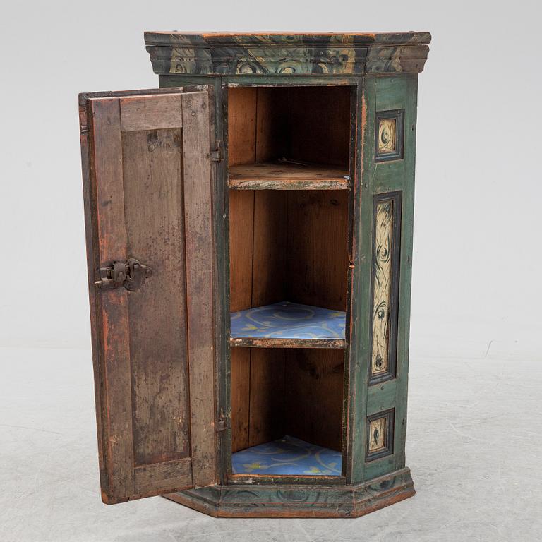 A painted corner cabinet, dated 1810.