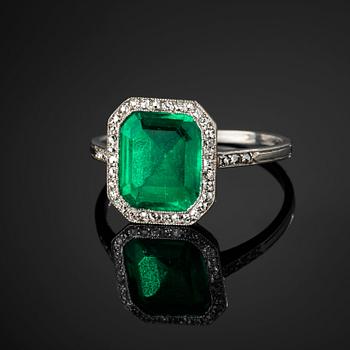 A platinum ring set with a Colombian step-cut emerald and old-cut diamonds in a fitted case from Cartier.