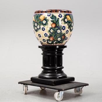 A handpainted faience, urn on wooden pedestal. Aluminia, Denmark. Dated 1910.