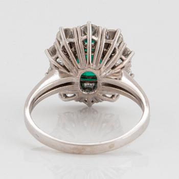 An 18K white gold ring set with a faceted emerald ca 1.15 cts and round brilliant-cut diamonds.