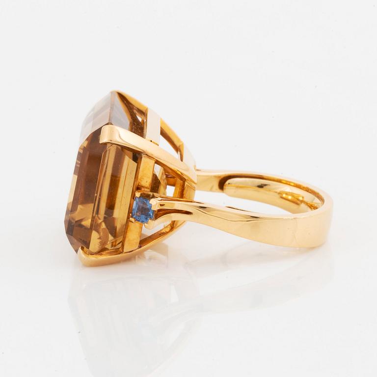 An 18K gold ring set with a faceted citrine and two sapphires.