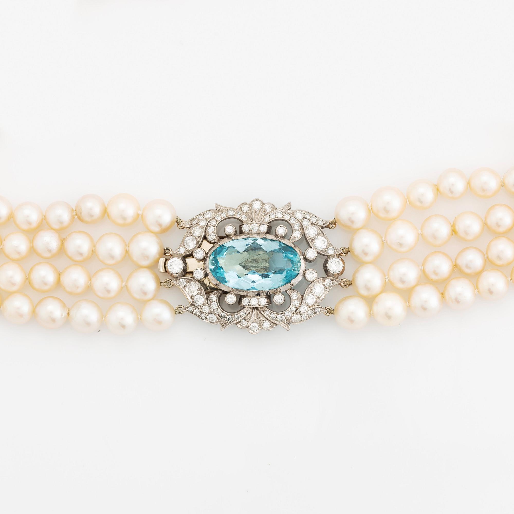 A four strand cultured pearl necklace with a clasp in 14K gold set with a faceted aquamarine.