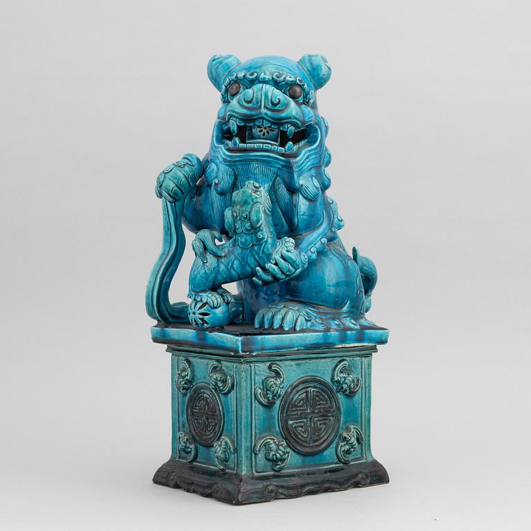 A Chinese seated buddhist lion on a plinth, 20th century.