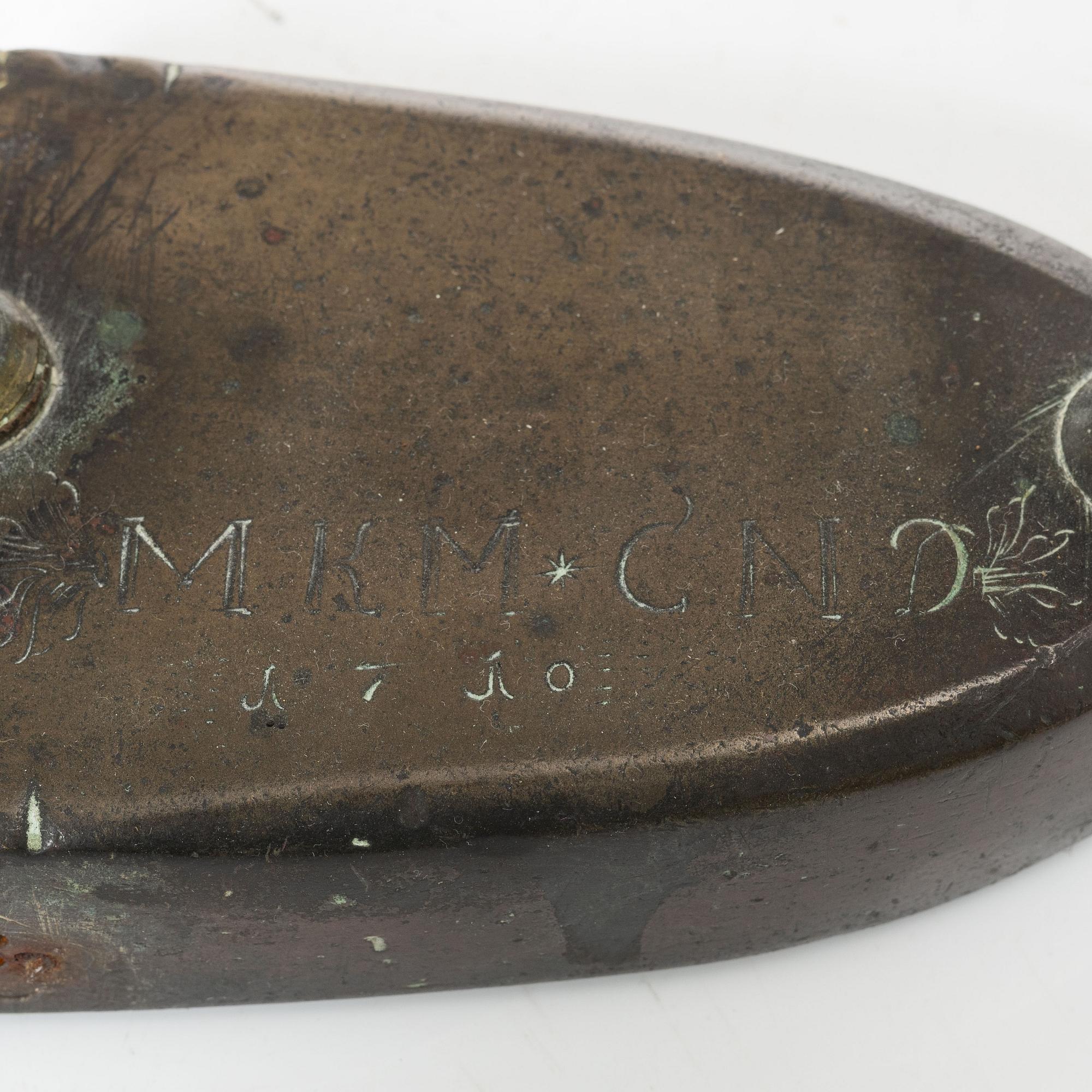A brass clothes iron, dated 1710.