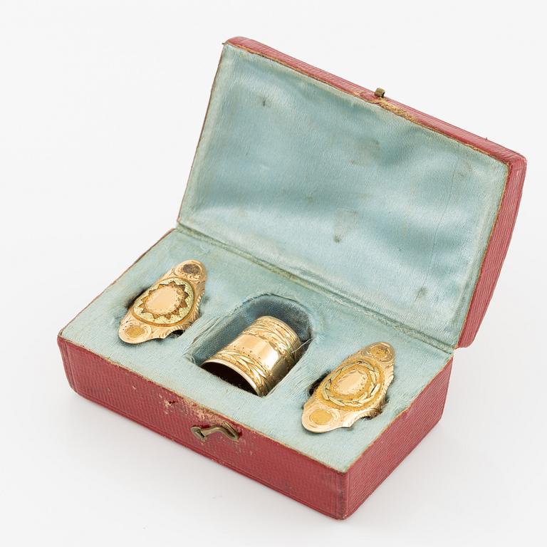 Thimble, finger guard and two rings, 18K gold, with fitted case.