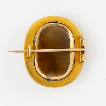 A brooch in 18K gold with a hardstone cameo.