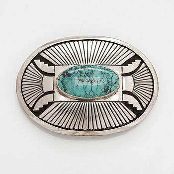 Chester Benally, a silver belt buckle with a turquoise, Navajo.