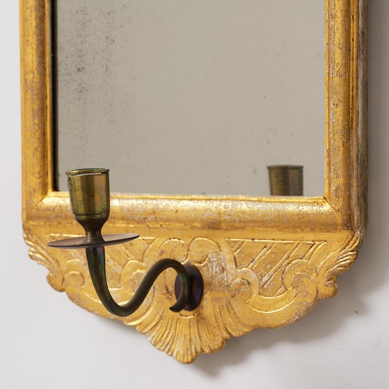 A matched pair of rococo giltwood one-branch girandole mirrors, Stockholm, late 18th century.