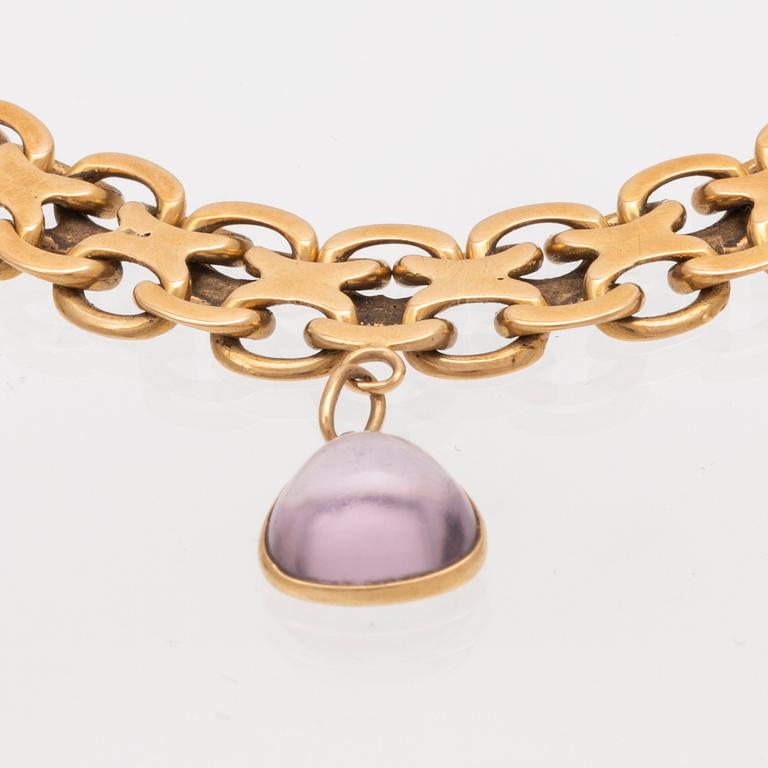 An 18K gold x-link bracelet with cabochon cut amethyst.