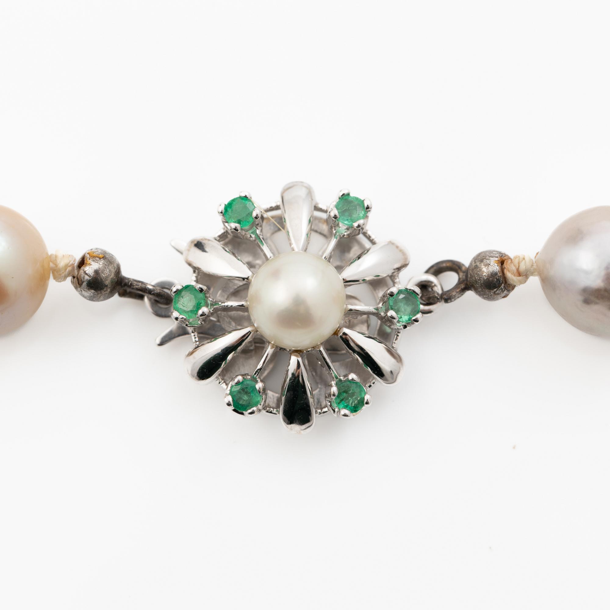 Long cultured pearl necklace with an 18K white gold clasp set with emeralds.