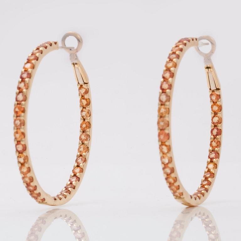 A pair of orange-yellow sapphire hoop earrings.