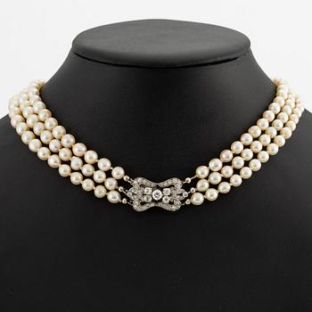 A three-strand cultured pearl necklace with an 18K white gold clasp with round brilliant-cut diamonds.