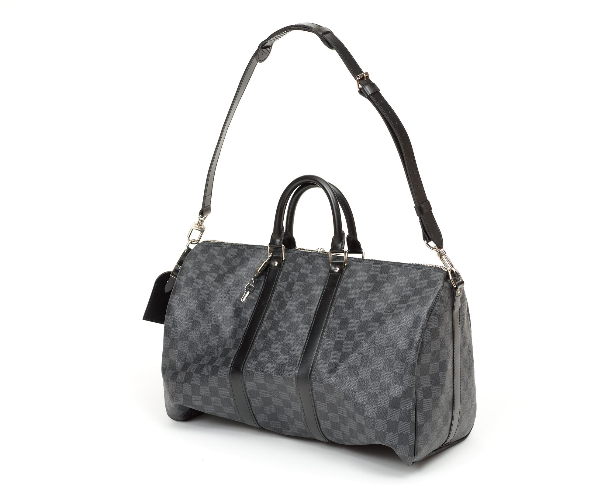 A black damier ebene canvas weekend bag by Louis Vuitton.