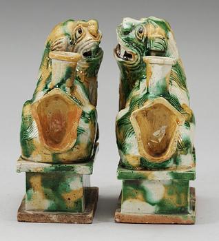 A pair of green and yellow glazed bisquit cencers, in the shape of sitting Buddhist lions, Qing Dynasty, Kangxi (1662-1722).