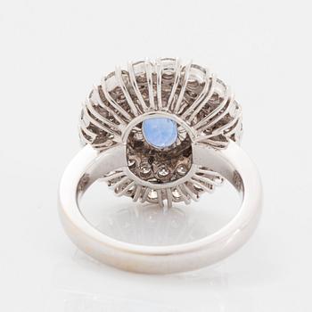 An 18K white gold ring set with an oval faceted sapphire and round brilliant-cut diamonds.