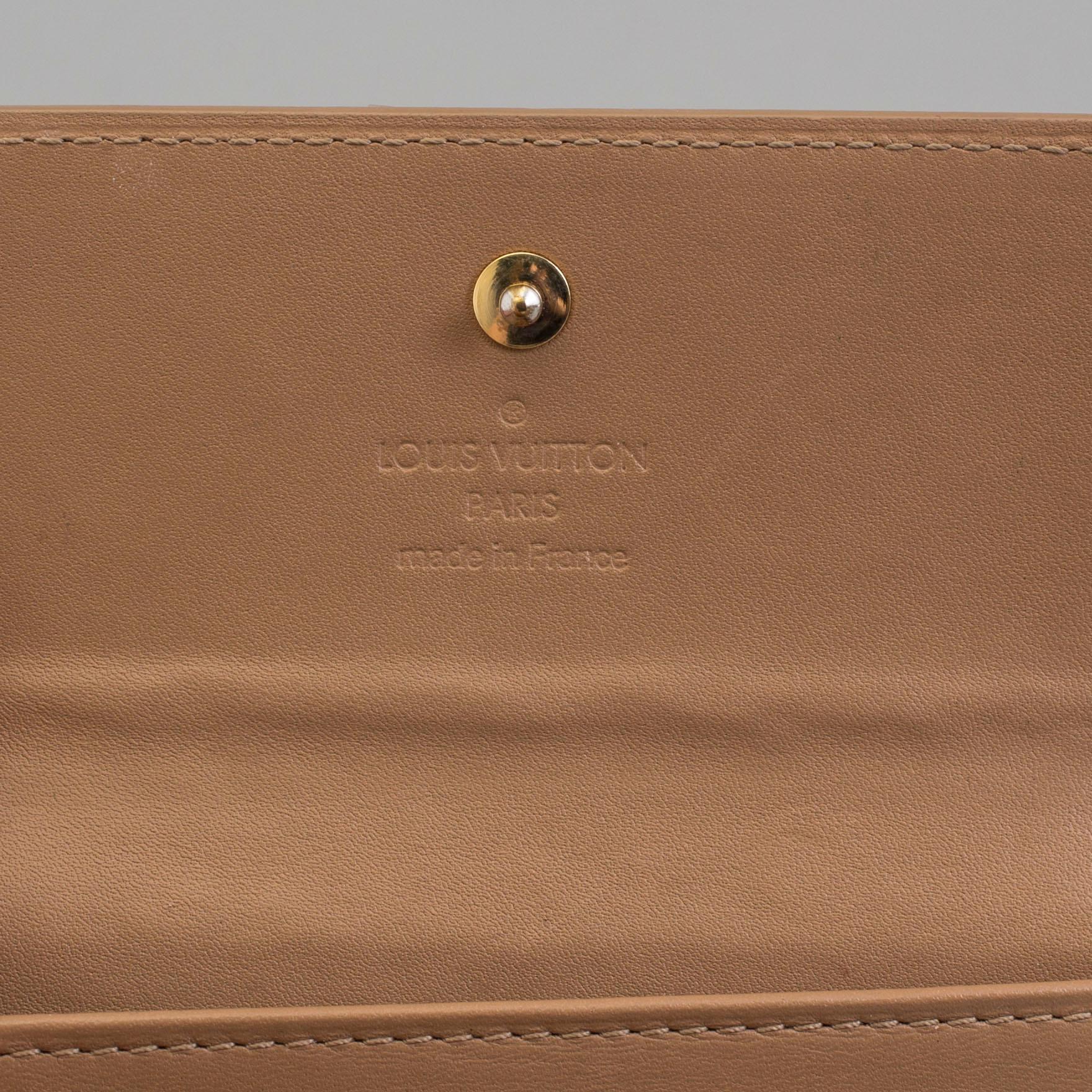 A beige monogram vernis wallet by Louis Vuitton.