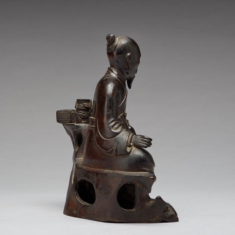 A bronze sculpture of a seated scholar with books, Qing dynasty (1644-1912).