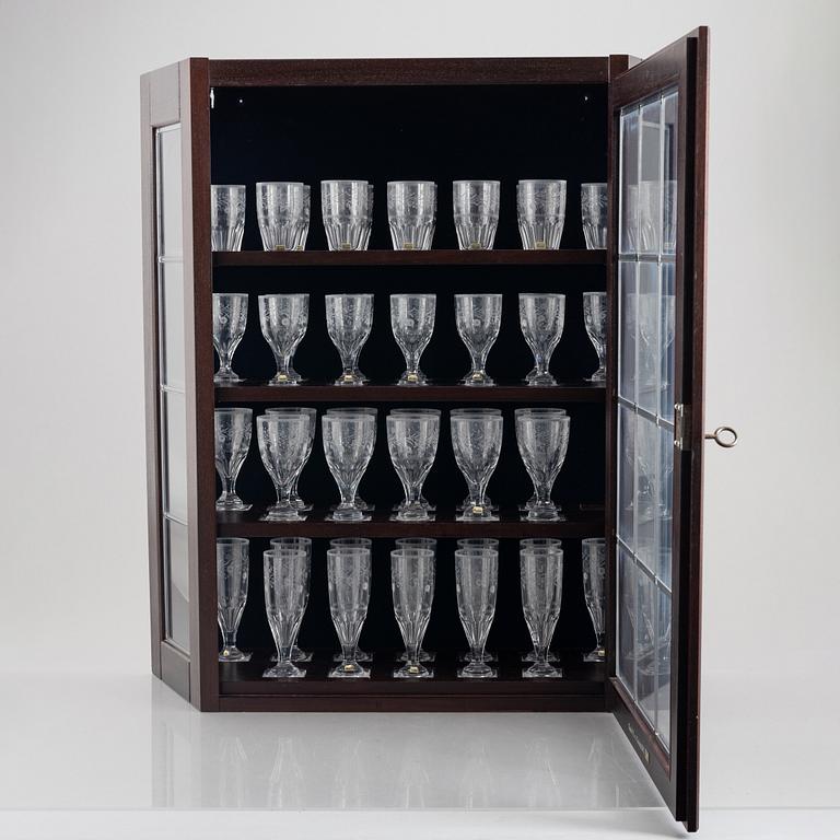 A display cabinet with a 47-piece glass service, "Koskull" from Kosta, Sweden.