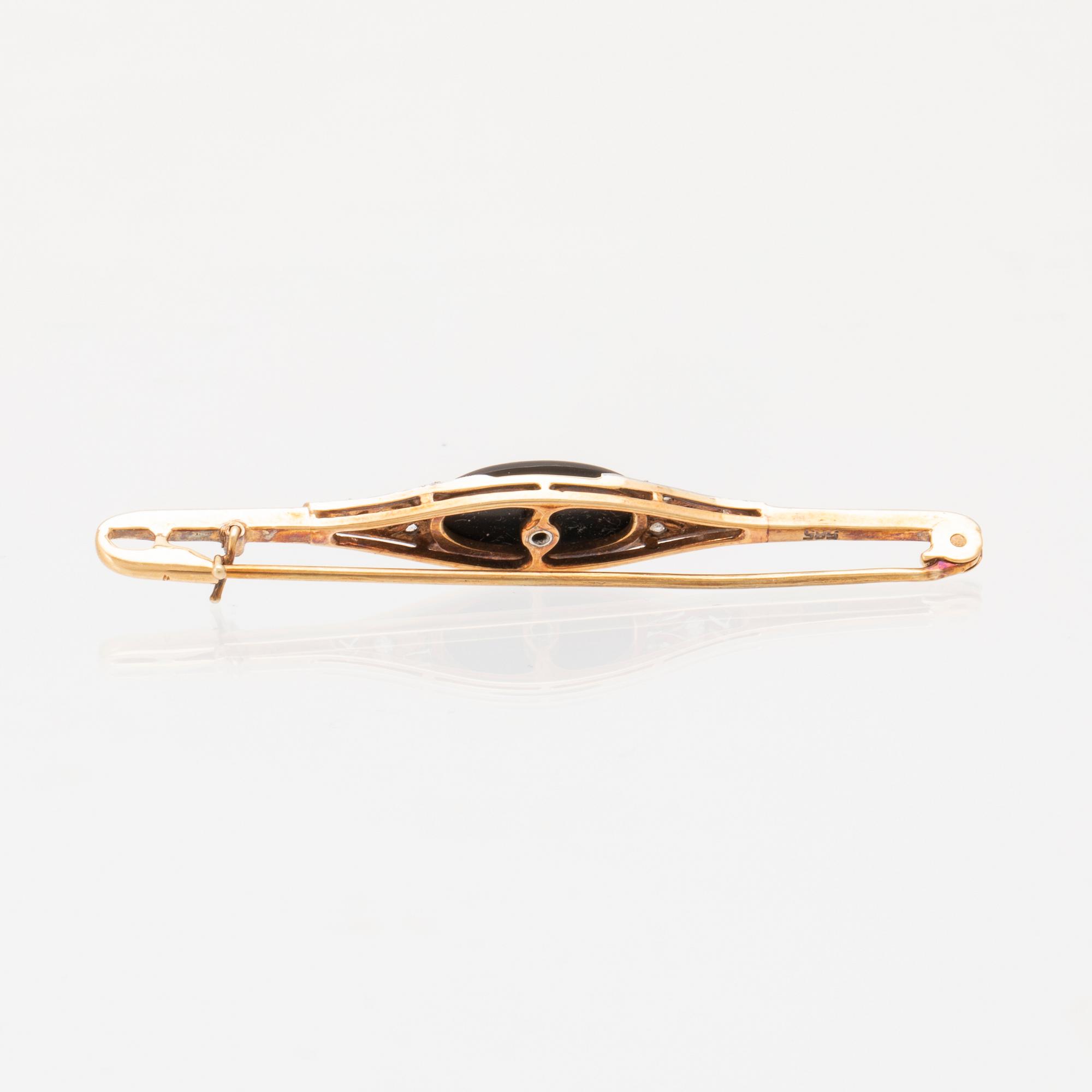 A 14K white and red gold brooch set with round brilliant-cut and rose-cut diamonds and a black stone.