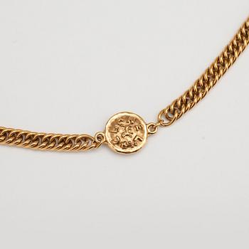 CHANEL, a gold colored medallion necklace.