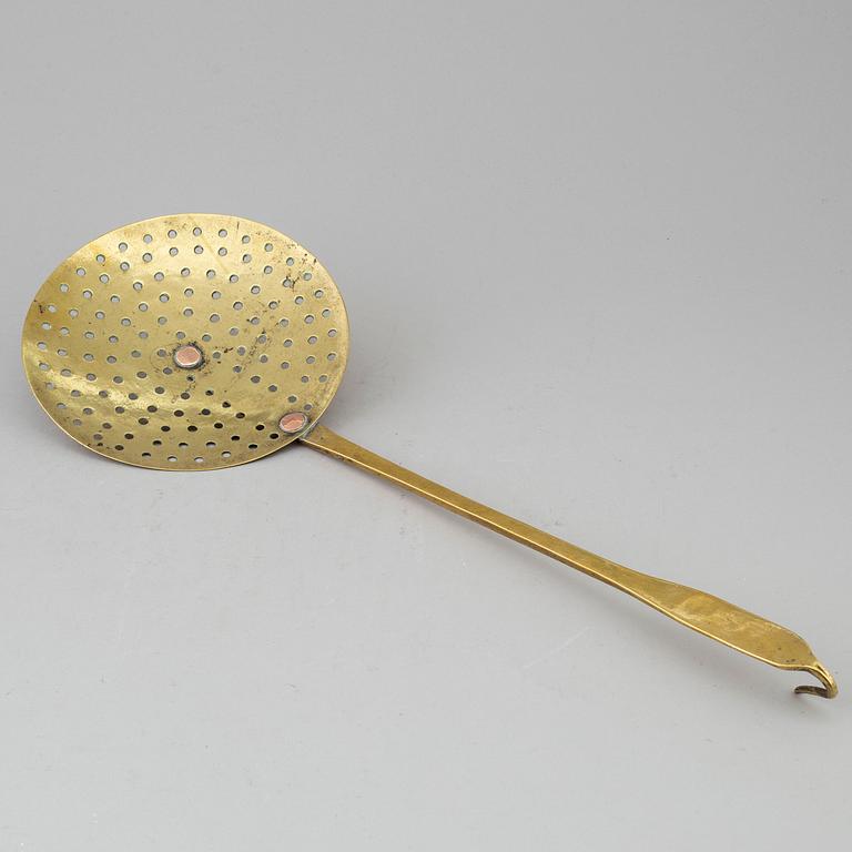 An 18th century brass strainer.