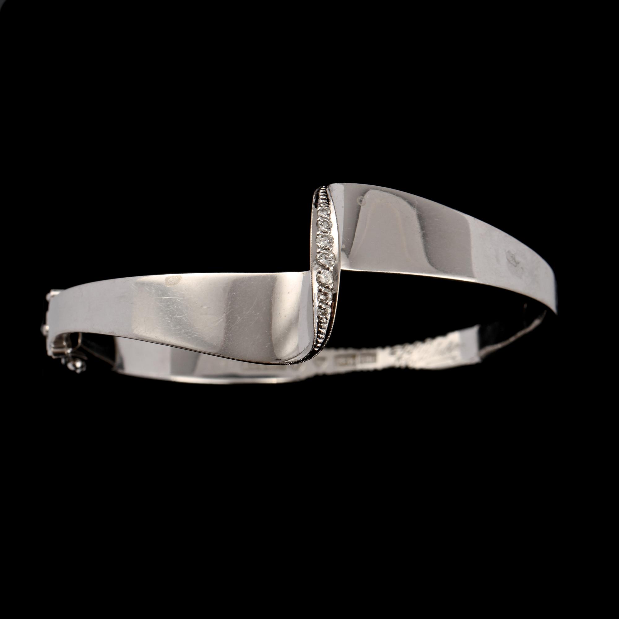 ARMRING, 18k vitguld med 7 briljantslipade diamanter, tot 0.17 ct, KE Palmberg, Alton, Falköping, 1975. Vikt 21 g.