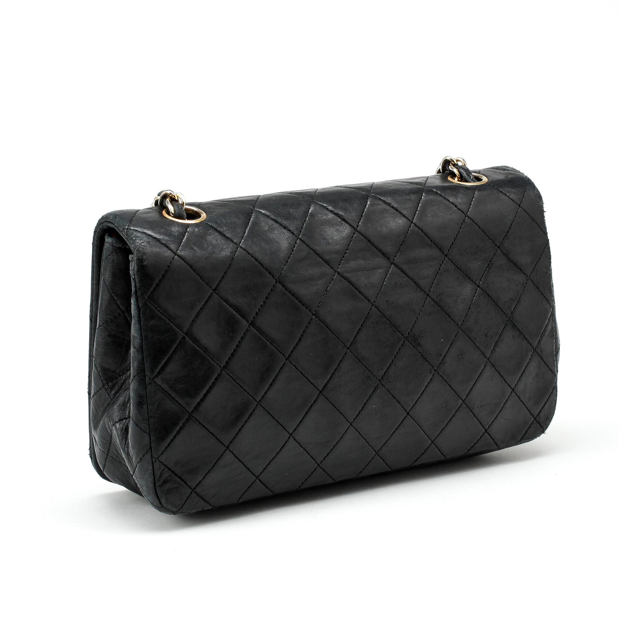CHANEL, a black leather quilted purse with shoulder strap.