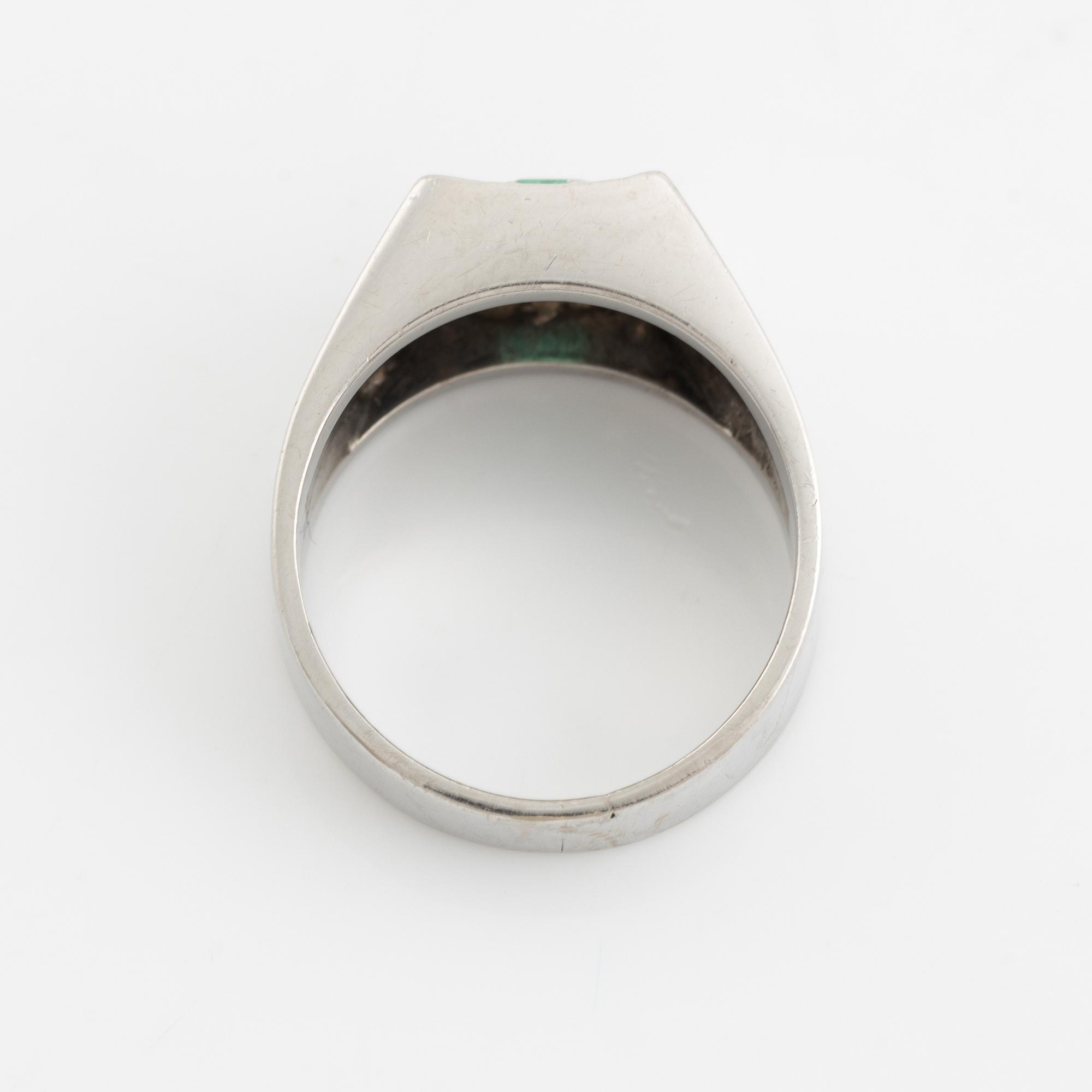 An 18K white gold ring set with a step-cut emerald and round brilliant-cut diamonds.