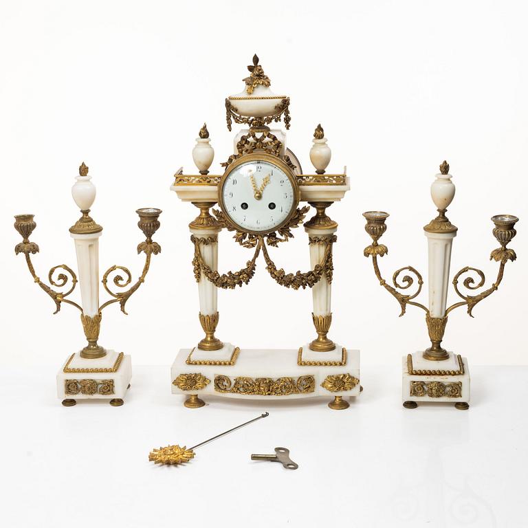 A Louis XVI-style mantle clock and a pair of candelabras. Early 20th century.