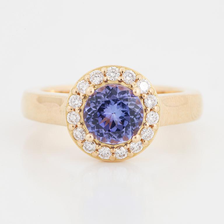 An 18K gold ring set with a faceted tanzanite and round brilliant-cut diamonds.