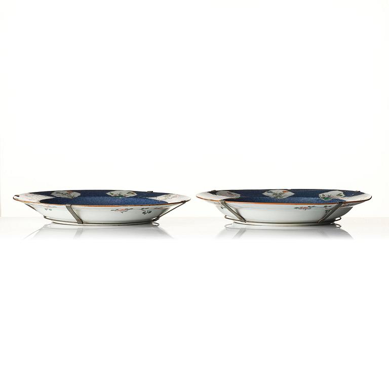 A fine pair of large powder-blue-ground famille-verte 'flowering garden' dishes, Qing dynasty.