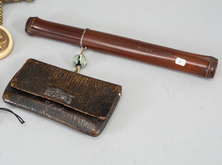 Two Japanese tobacco pouches, one with a pipecase and pipe, Meiji period (1868-1912), and a carved ornament.