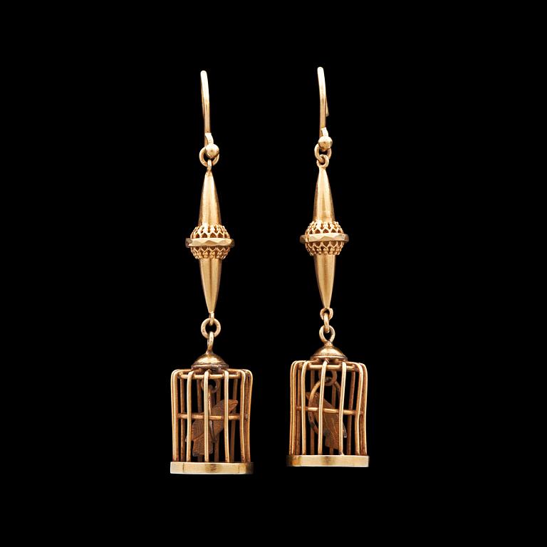 A pair of gold earrings in the shape of bird cages.