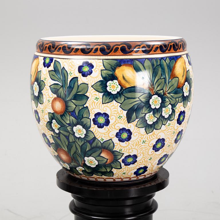 A handpainted faience, urn on wooden pedestal. Aluminia, Denmark. Dated 1910.