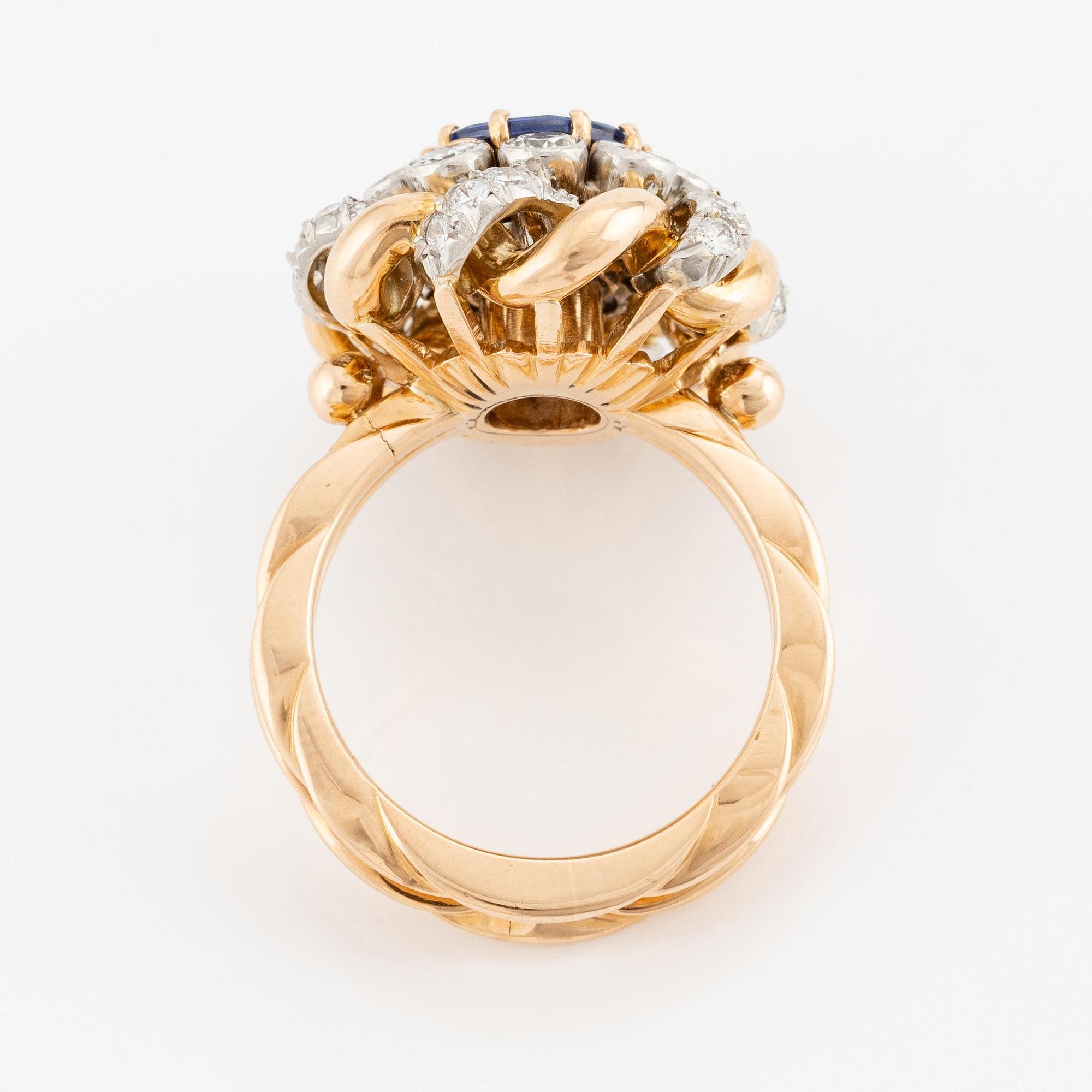 An 18K gold  ring with a sapphire and round brilliant-cut diamonds.