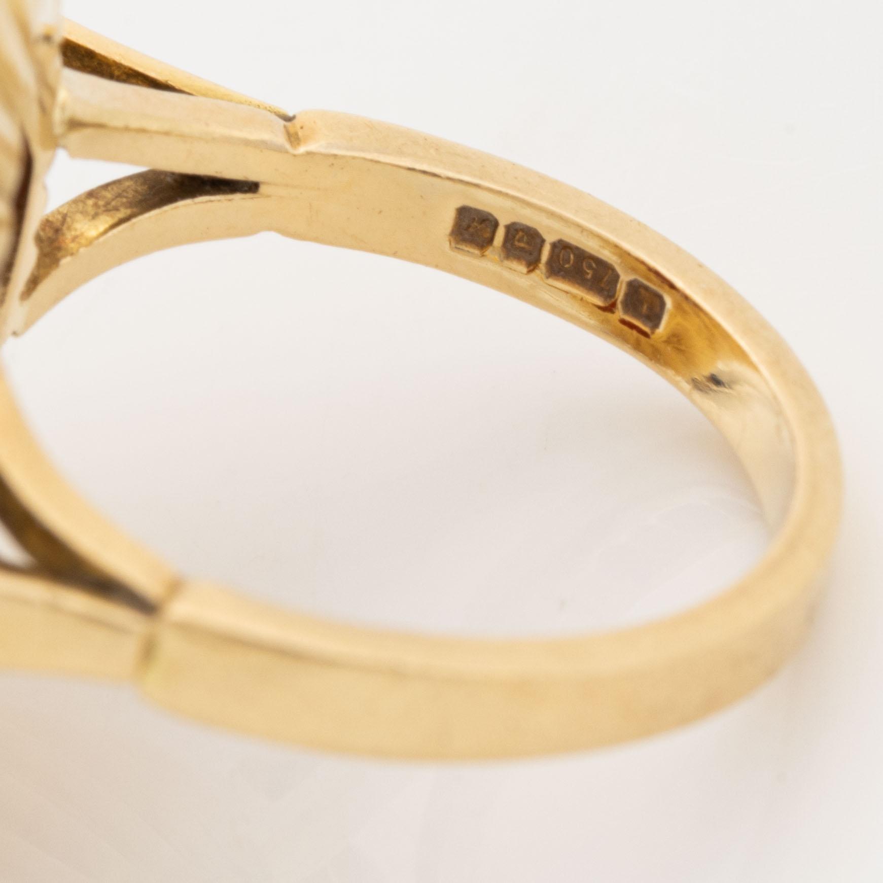An 18K gold ring set with a hardstone cameo.