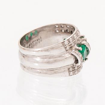 An 18K white gold ring set with oval cut emeralds and round brilliant cut diamonds.