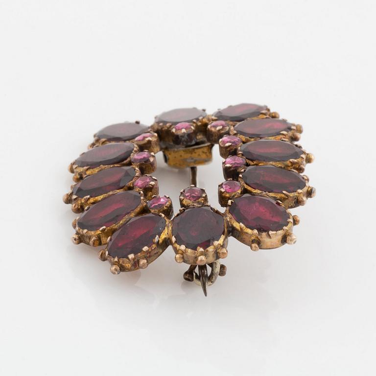 A silver and gold brooch set with faceted garnets.