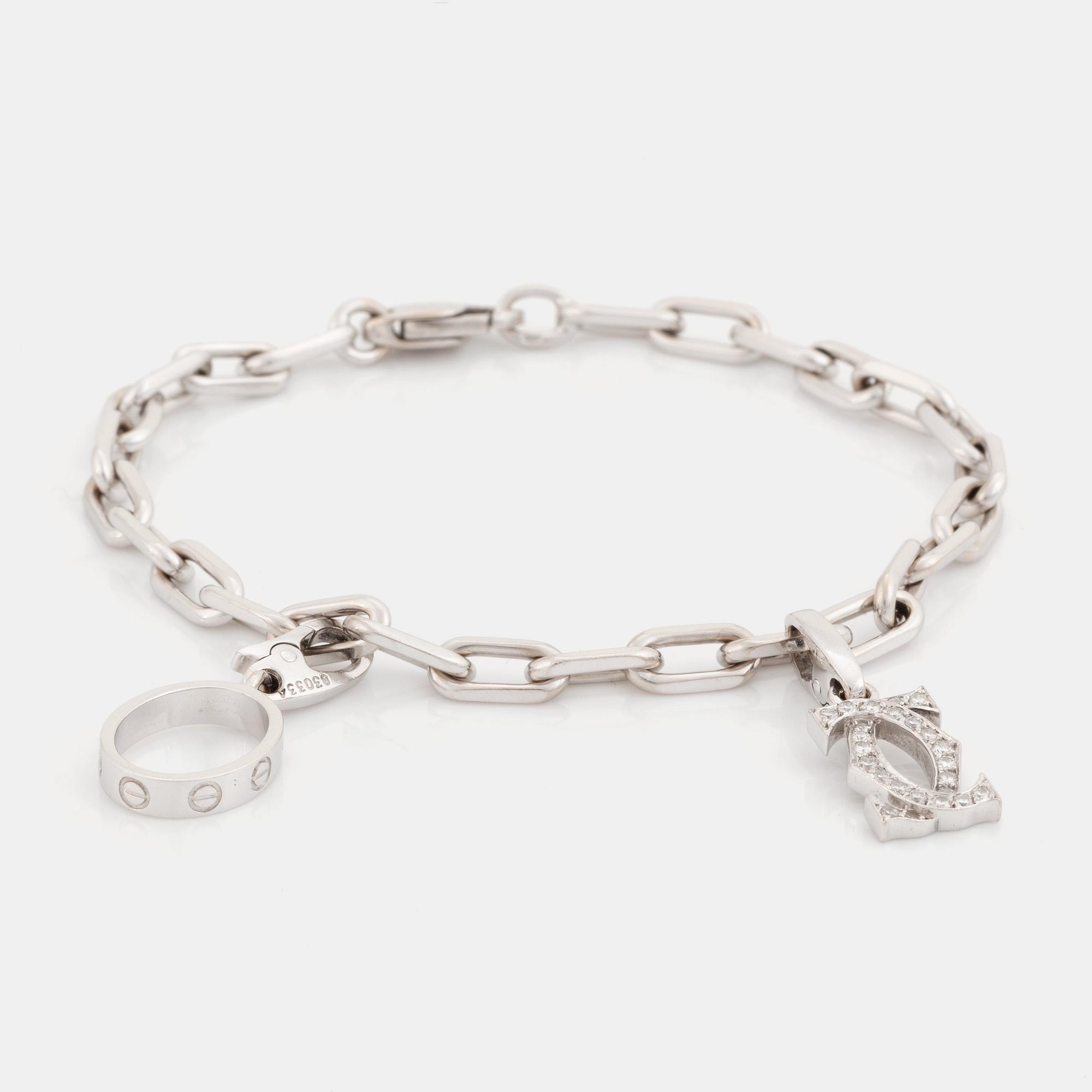 An 18K white gold Cartier "Spartacus" bracelet with two charms.